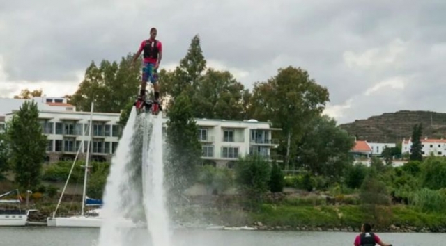 chico practicando flyboard mientras uno le mira desde una moto de agua.jpg